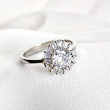 Bague en argent rhodié avec pierre centrale et halo de zircons Bague en argent rhodié avec pierre centrale et halo de zircons