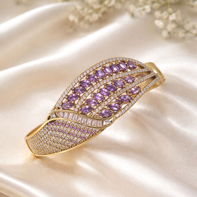 Affirmez votre élégance avec ce bracelet antique en bronze et argent, une pièce luxueuse inspirée des bijoux royaux d’autrefois. Son design richement orné de pierres violettes taillées en forme marquise, rehaussées de cristaux lumineux, crée un jeu de lumière somptueux et captivant.

La structure finement travaillée associe la chaleur du bronze antique à l’éclat raffiné de l’argent, offrant un bijou à la fois noble et intemporel. Chaque détail reflète un savoir-faire artisanal d’exception, faisant de ce bra