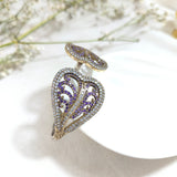 Laissez parler votre élégance avec ce bracelet antique en bronze et argent, une création raffinée au design romantique et intemporel. Orné de motifs en forme de cœur, finement ajourés et sertis de pierres violettes et de cristaux scintillants, ce bijou évoque le luxe des parures anciennes et la délicatesse de l’art artisanal.