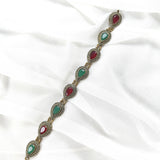 Gourmette antique en bronze avec pierres vertes et rouges