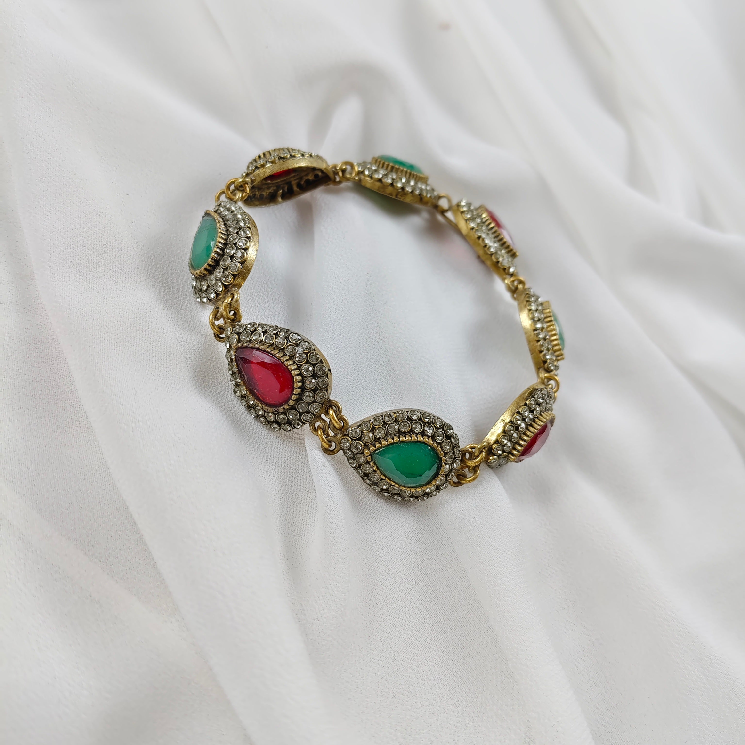 Gourmette antique en bronze avec pierres vertes et rouges